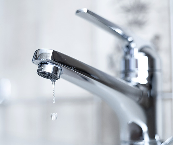 Shiny chrome bathroom faucet with a dripping water drop