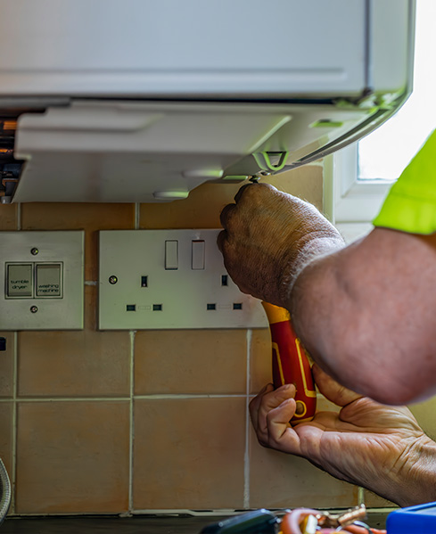 A technician working on a boiler installation with tools in a residential setting