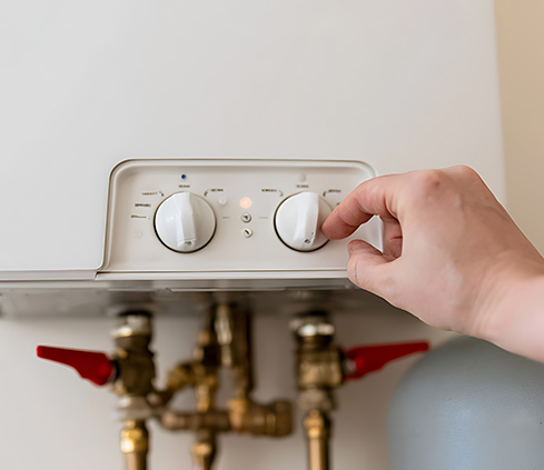 Boiler control panel adjustment with visible dials and valves.